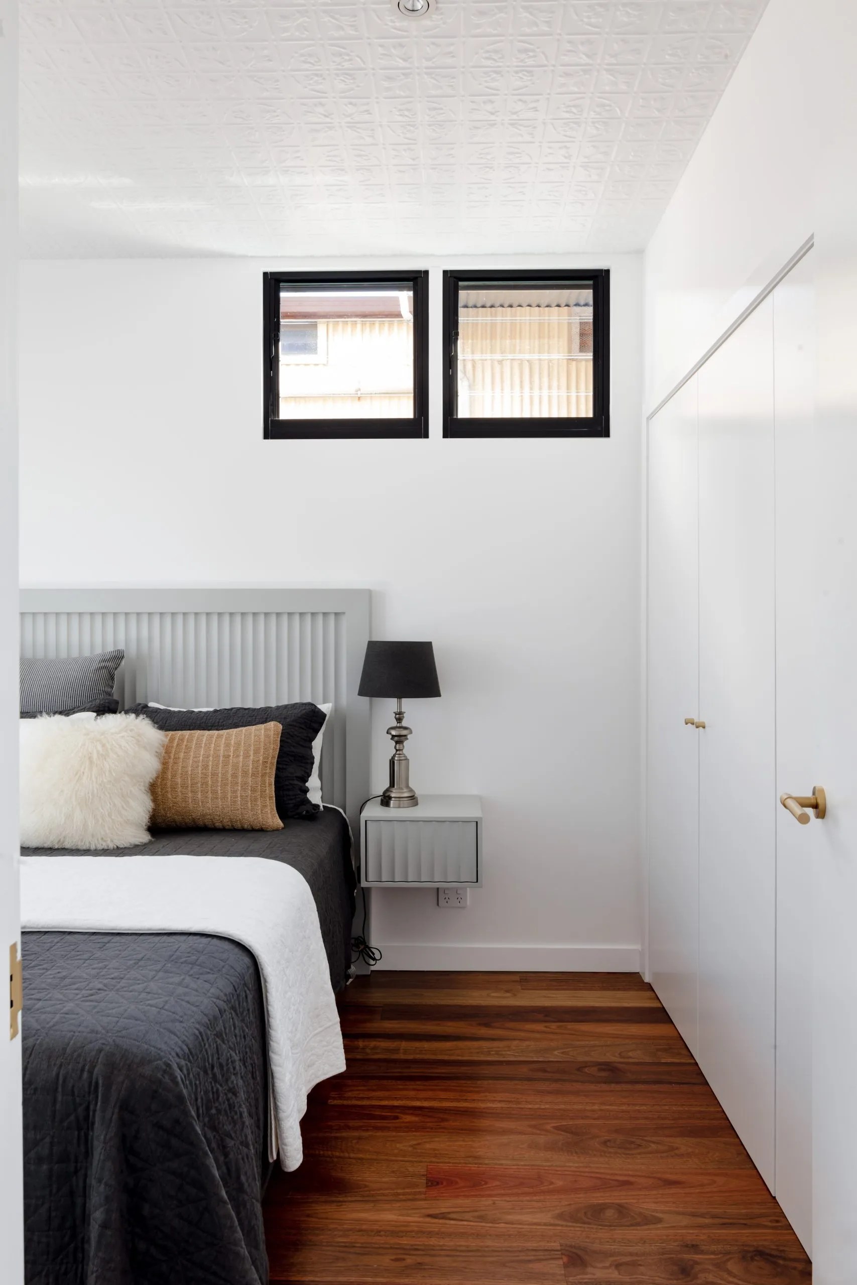 A white bedroom with wooden floors and a bed.