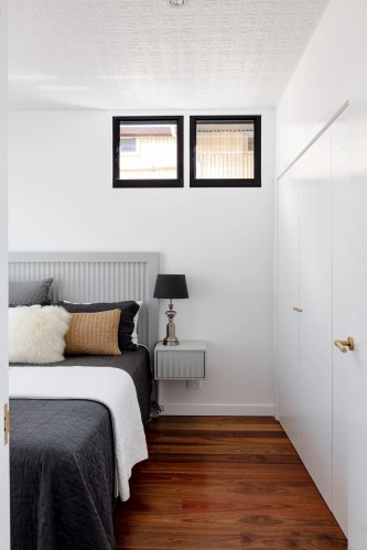 A white bedroom with wooden floors and a bed.